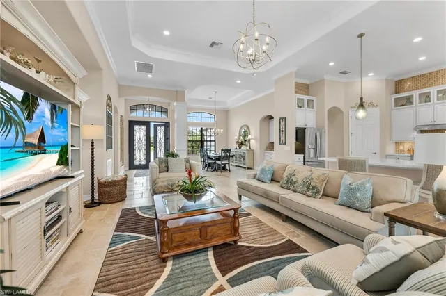 a living room with furniture kitchen view and a chandelier