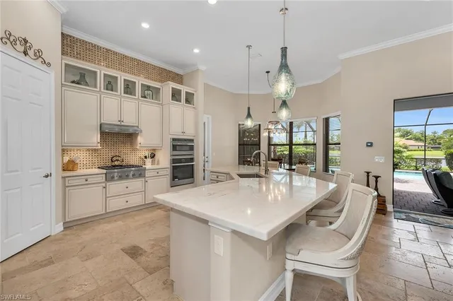 a large kitchen with granite countertop a large counter top appliances and cabinets