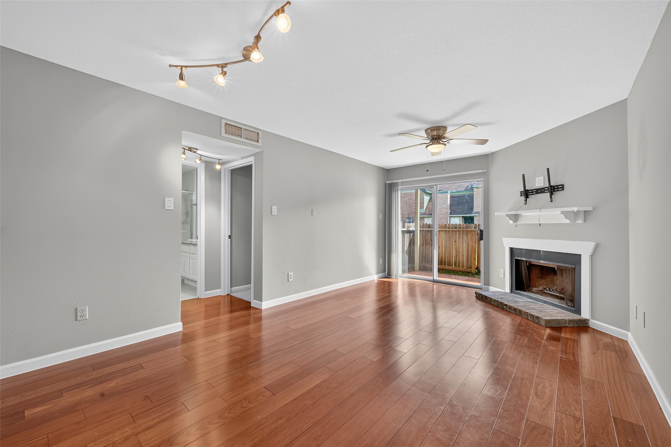 a view of an empty room with wooden floor fireplace and a window