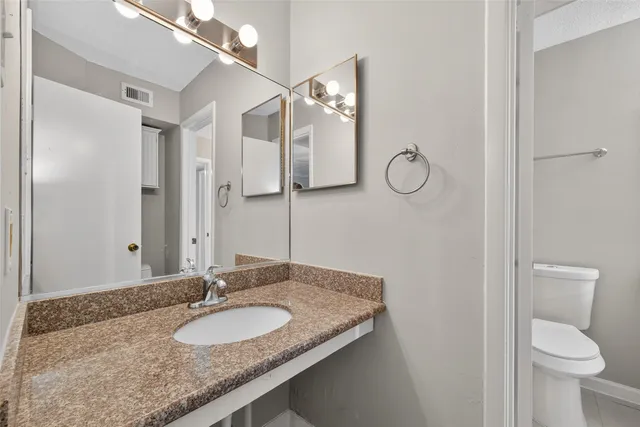 a bathroom with a granite countertop sink toilet and a mirror