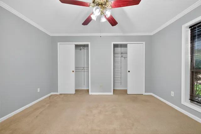 a view of an empty room with chandelier fan and window