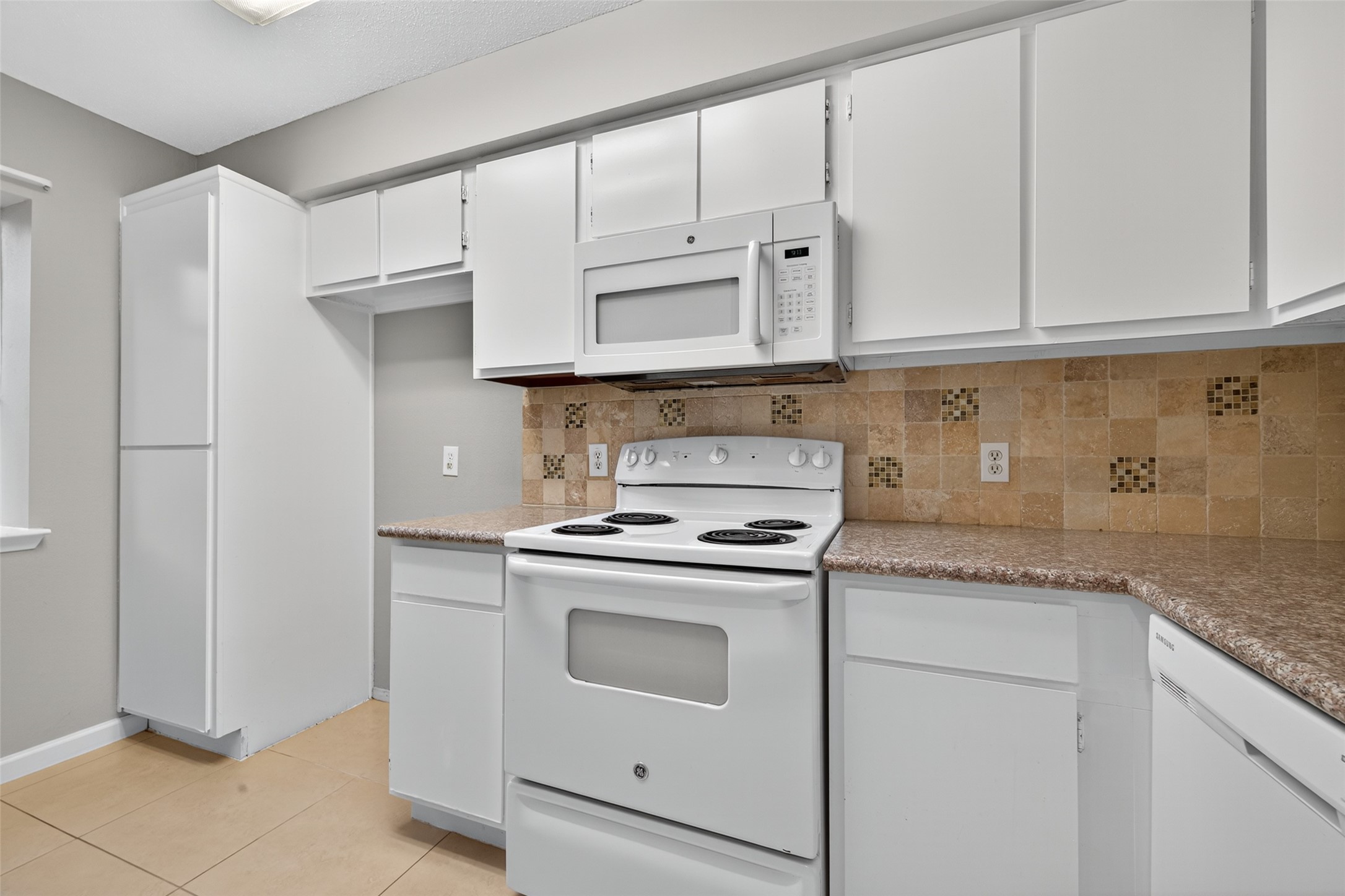 18800 Egret Bay Boulevard, Unit 1207 Webster, TX 77058 - Photo 7 of 30 a kitchen with granite countertop white cabinets and a stove