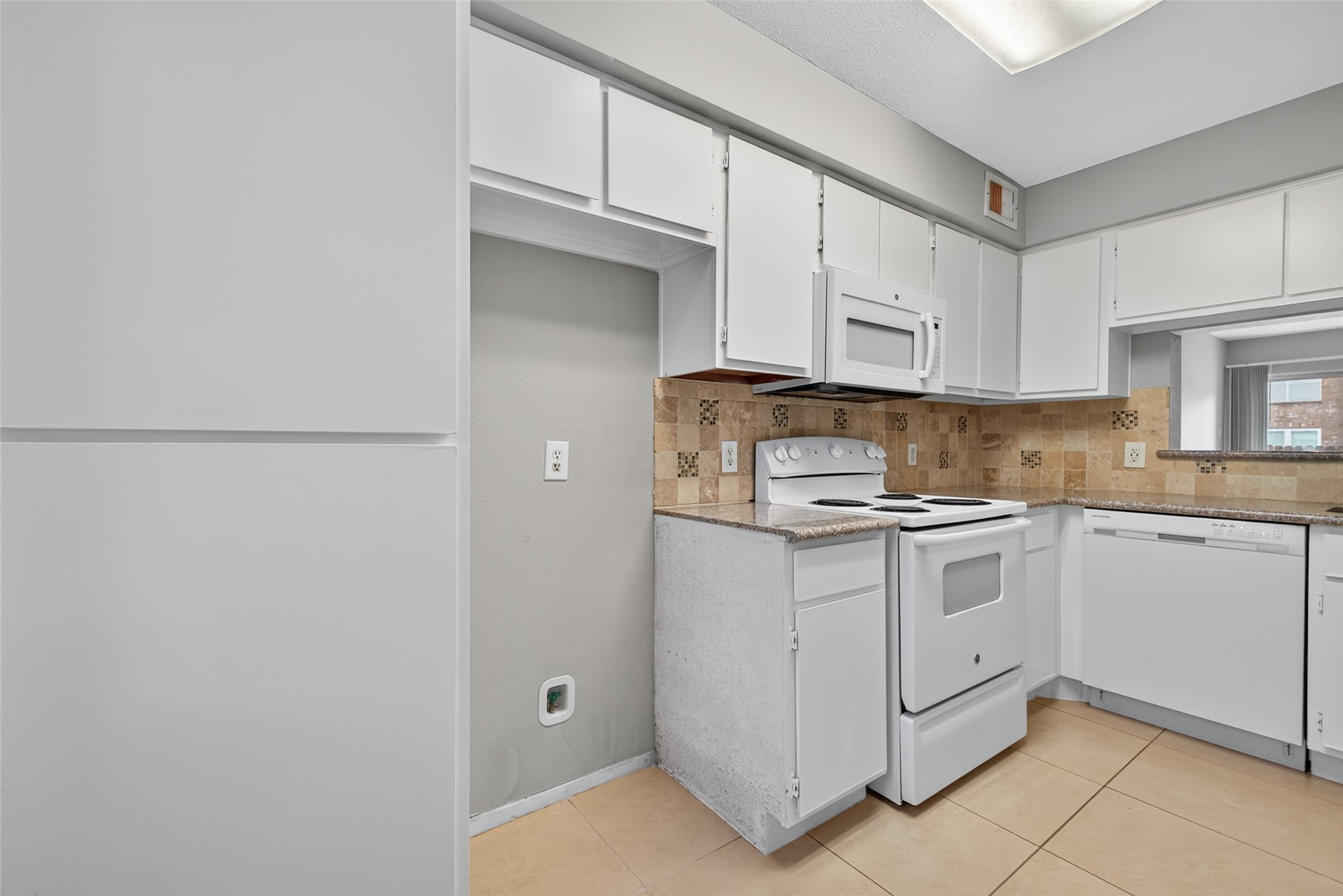18800 Egret Bay Boulevard, Unit 1207 Webster, TX 77058 - Photo 8 of 30 a kitchen with granite countertop white cabinets and white appliances