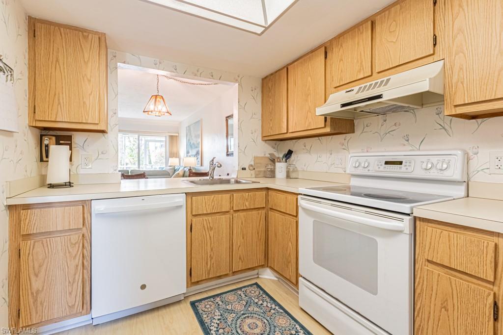 1022 Manatee Road, Unit D107 Naples, FL 34114 - Photo 19 of 43 a kitchen with cabinets appliances a sink and a window