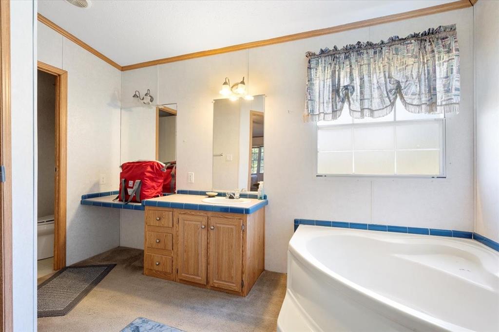 705 West Saunders Street Trenton, TX 75490 - Photo 11 of 37 a bathroom with a tub sink and a mirror