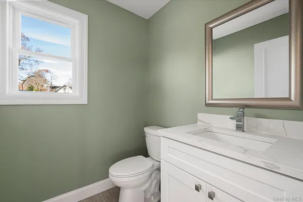 a bathroom with a granite countertop toilet a sink and mirror
