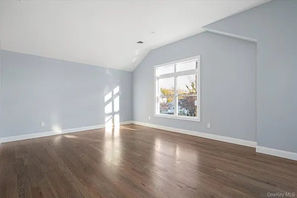 an empty room with wooden floor and window