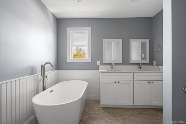 a bathroom with a white tub sink vanity and mirror