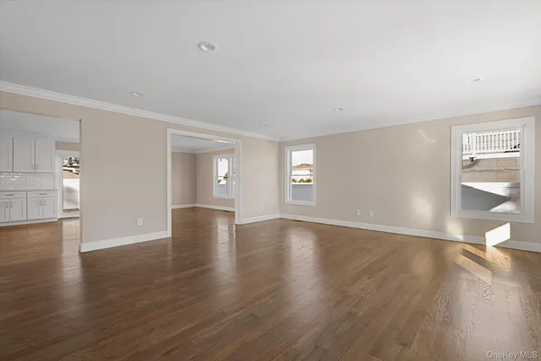a view of an empty room with window and wooden floor