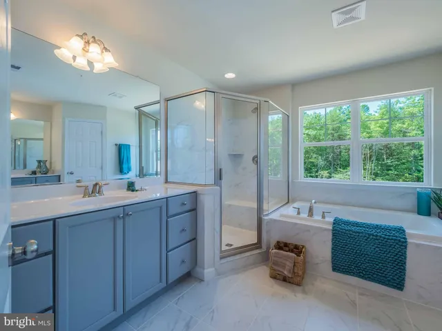 a spacious bathroom with a double vanity sink a large mirror and a shower