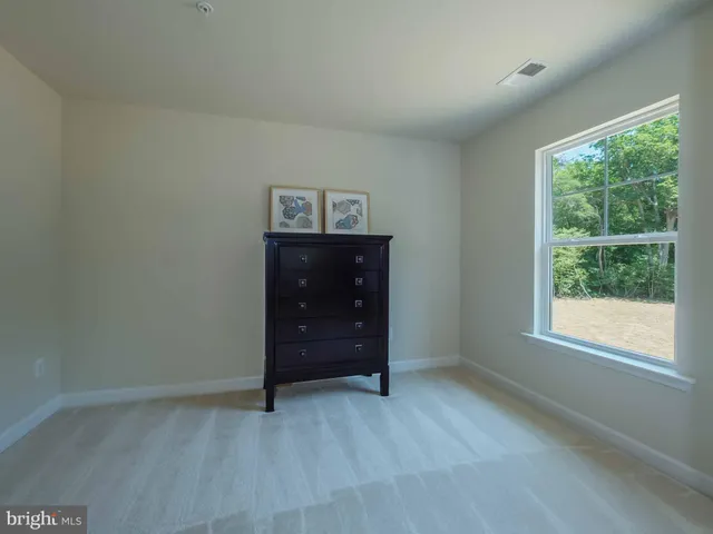 an empty room with a window and dresser
