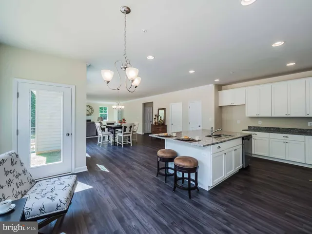 a large white kitchen with sink a stove and chairs