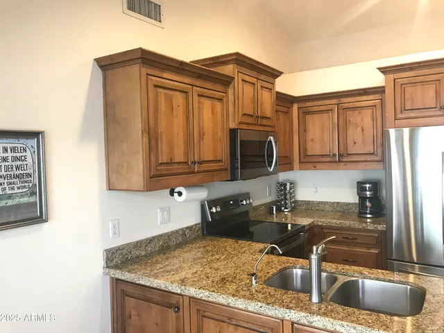 a kitchen with granite countertop a sink a stove and cabinets