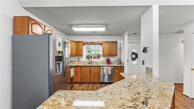 a kitchen with stainless steel appliances kitchen island granite countertop a refrigerator and a stove top oven