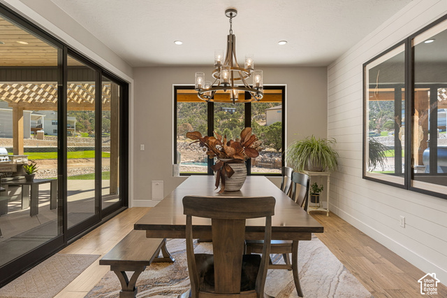 1192 East Ashdown Road Cedar City, UT 84721 - Photo 32 of 96 Spacious dining area featuring wood-finish flooring, a contemporary chandelier, recessed lighting, and expansive sliding glass doors leading to an outdoor patio with a pergola