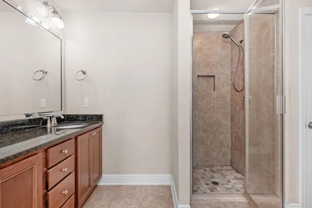 a bathroom with a granite countertop sink a mirror and shower