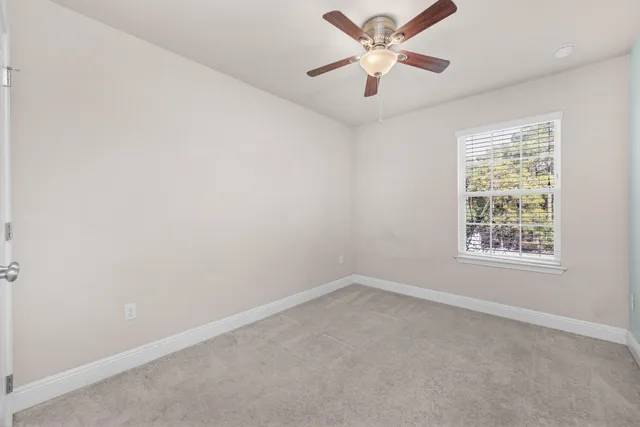 an empty room with a window and a fan