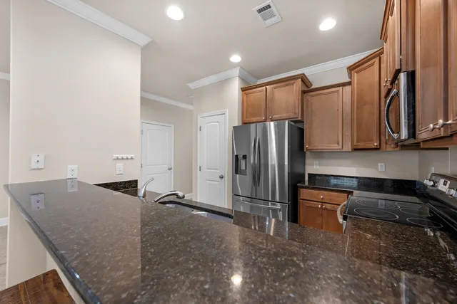 a kitchen with stainless steel appliances granite countertop a refrigerator a stove and a sink with wooden floor
