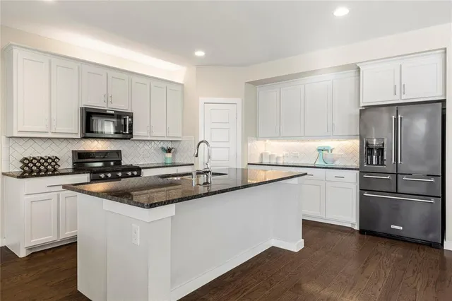 a kitchen with granite countertop a refrigerator stove top oven and sink