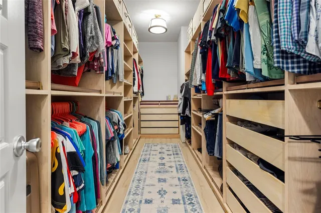 a view of walk in closet with clothes and shoes
