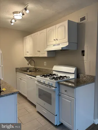 a kitchen with granite countertop white cabinets and stainless steel appliances