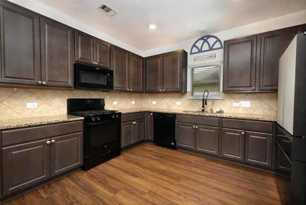 a kitchen with stainless steel appliances granite countertop wooden cabinets a stove top oven a sink and dishwasher