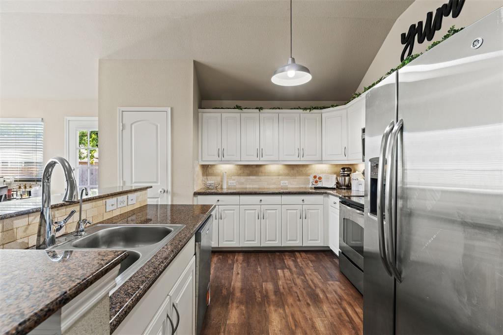 10313 Condor Loop Waco, TX 76708 - Photo 21 of 33 Well-appointed kitchen featuring white cabinetry, wood-finish flooring, stainless steel appliances, granite-look countertops, and an undermount sink