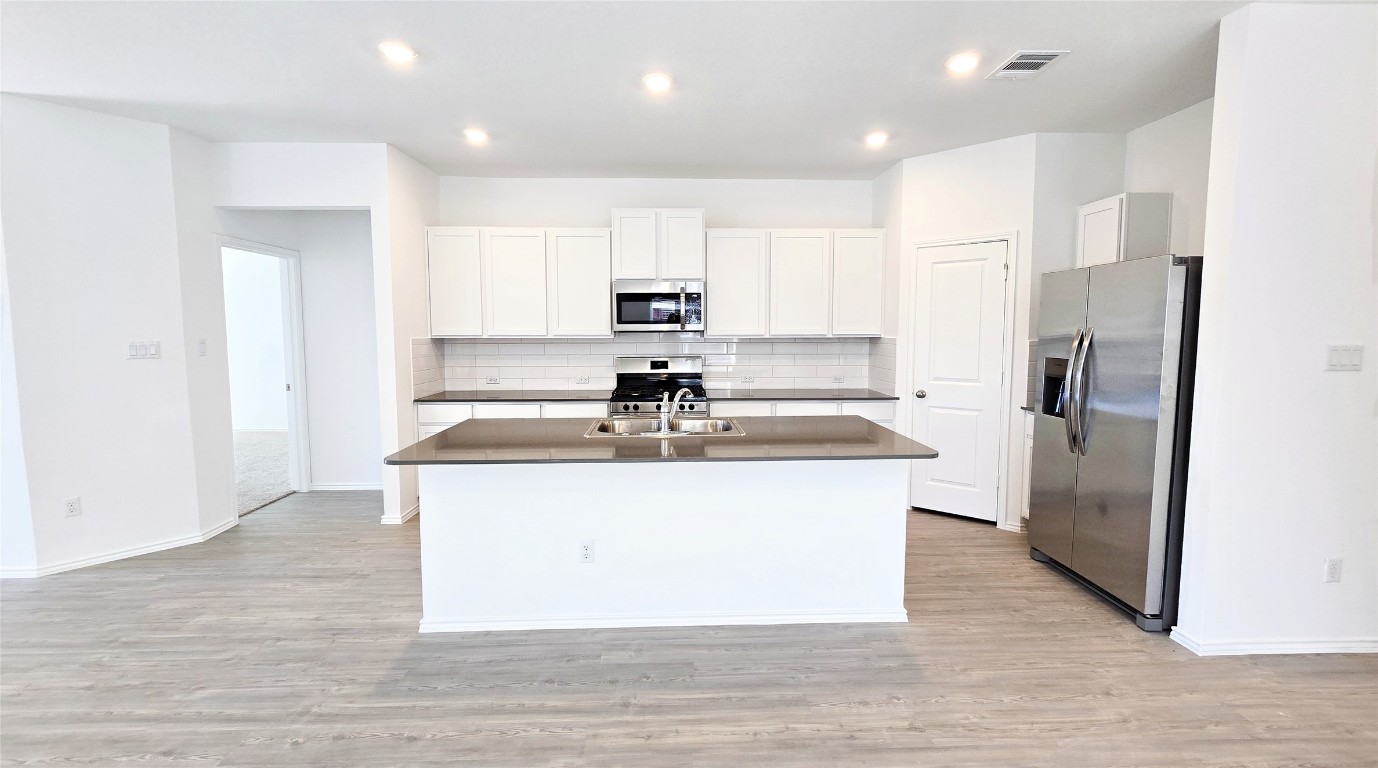 1637 Chapel Ranch Road Georgetown, TX 78628 - Photo 5 of 14 a view of kitchen with stainless steel appliances granite countertop a stove a refrigerator a sink and white cabinets with wooden floor