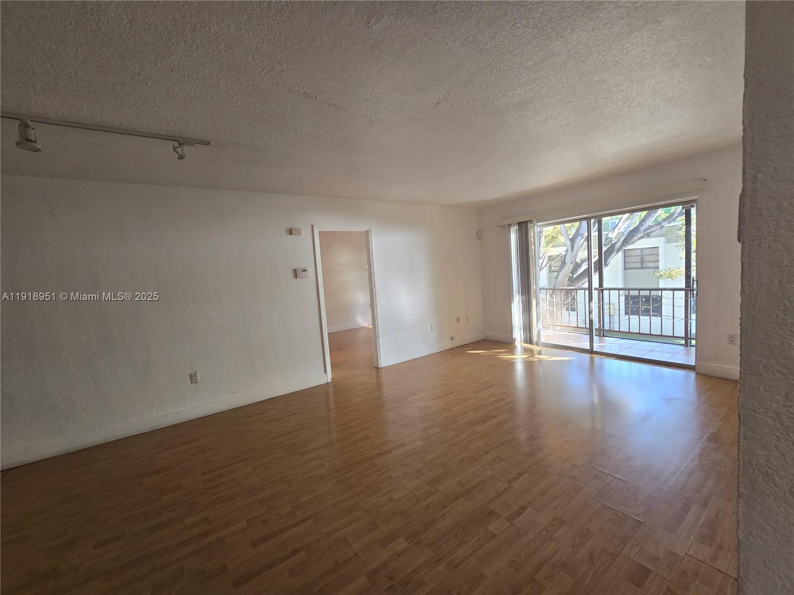 7925 Southwest 104th Street, Unit 201E Miami, FL 33156 - Photo 13 of 30 a view of an empty room with wooden floor and a window