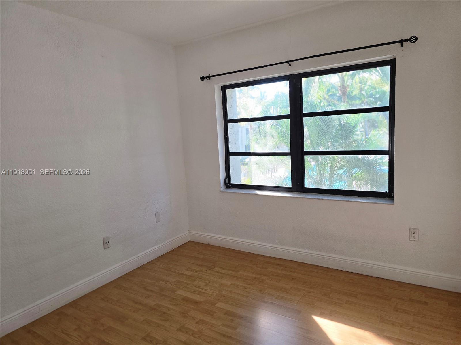7925 Southwest 104th Street, Unit 201E Miami, FL 33156 - Photo 17 of 32 an empty room with wooden floor and windows