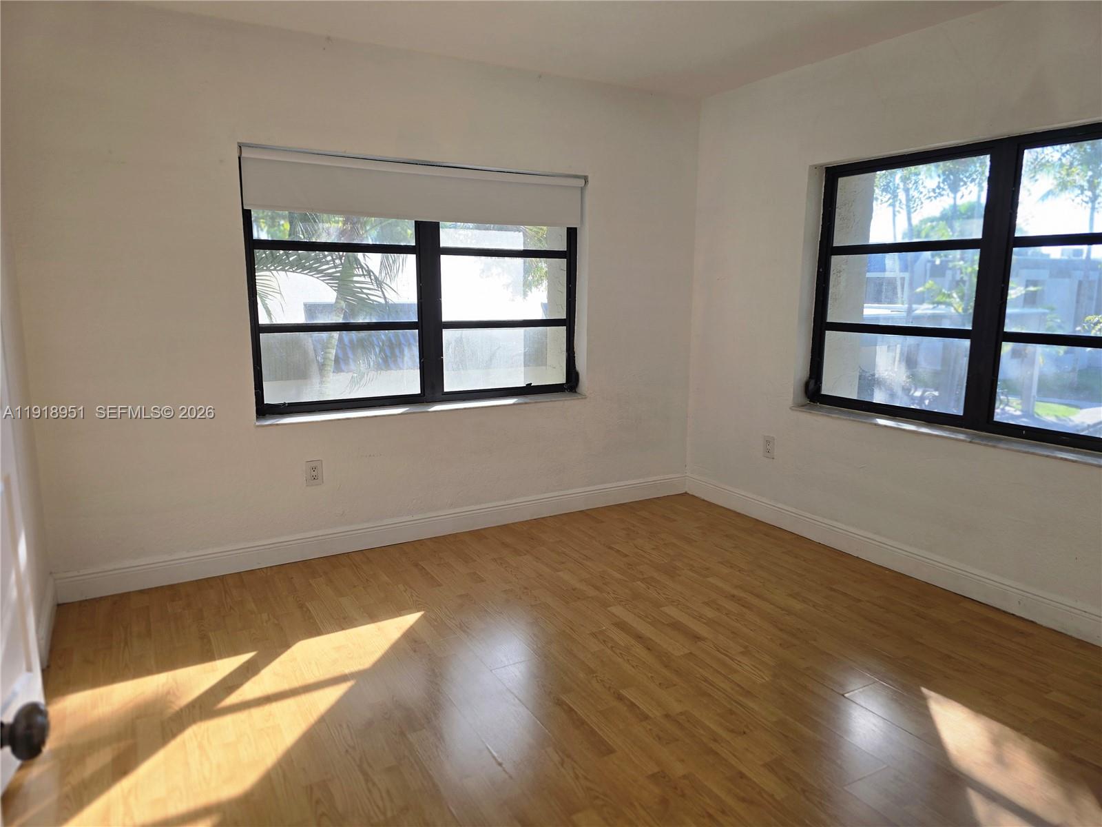 7925 Southwest 104th Street, Unit 201E Miami, FL 33156 - Photo 18 of 32 an empty room with wooden floor and windows