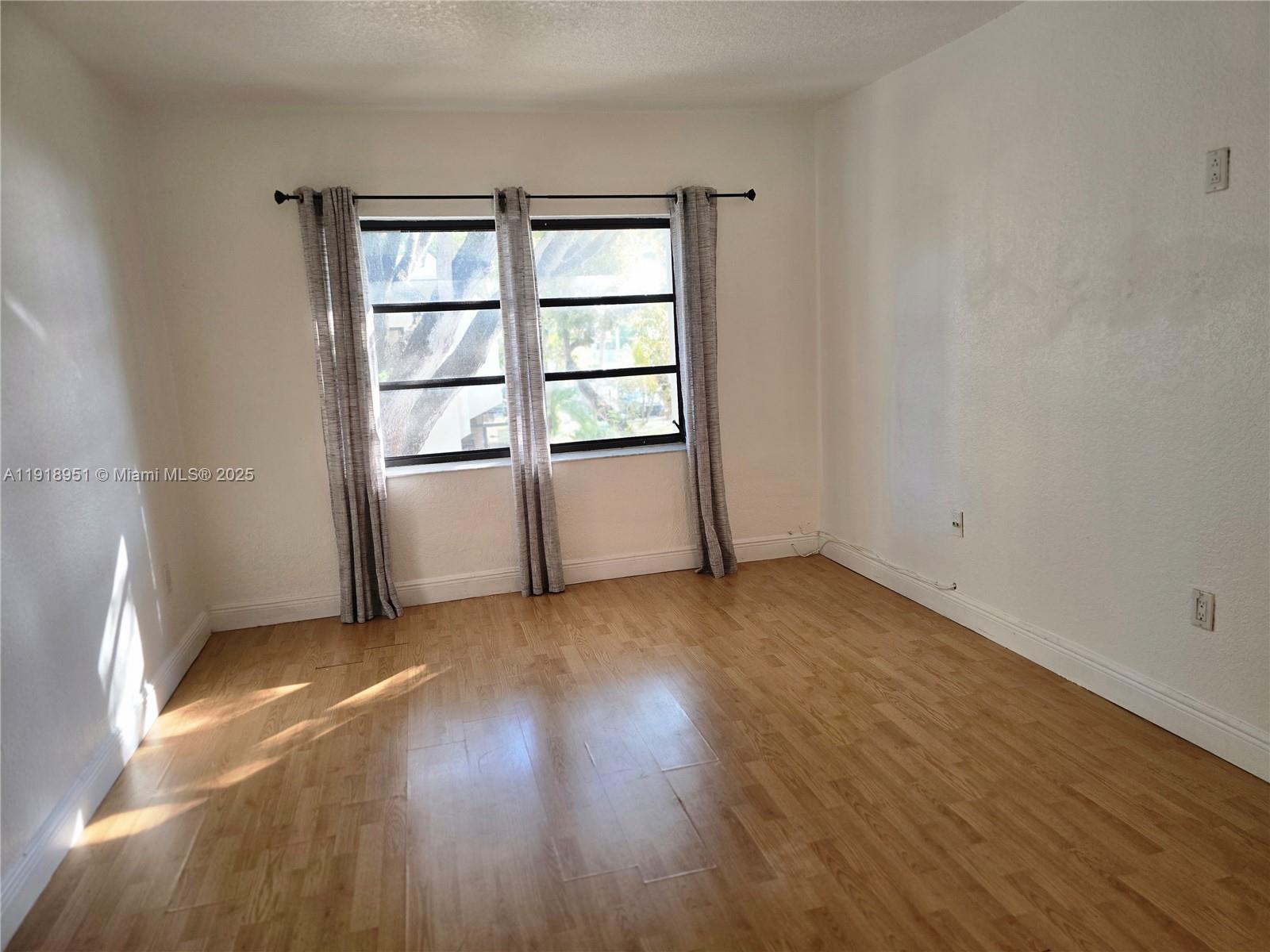 7925 Southwest 104th Street, Unit 201E Miami, FL 33156 - Photo 25 of 30 an empty room with wooden floor and window