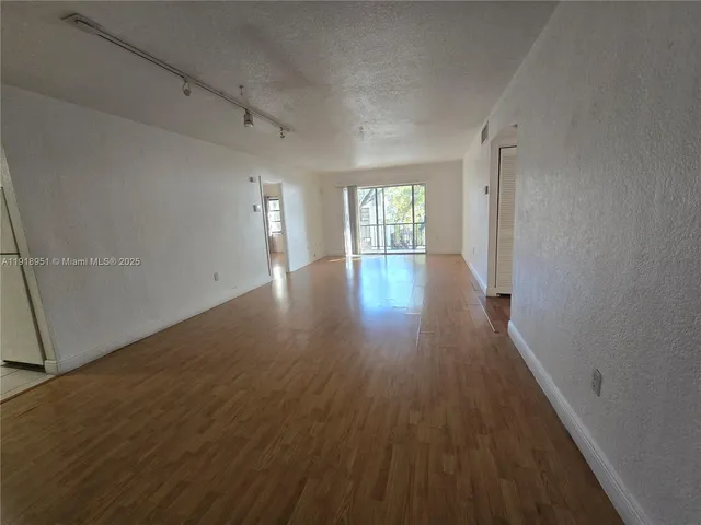 an empty room with wooden floor and windows with curtains