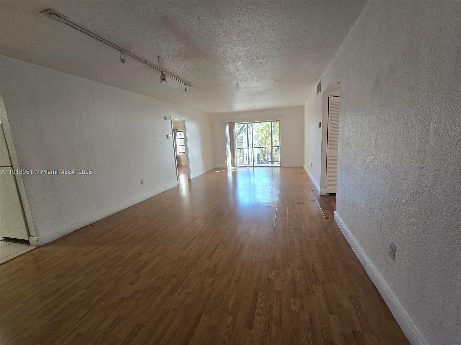 7925 Southwest 104th Street, Unit 201E Miami, FL 33156 - Photo 8 of 30 a view of an empty room with wooden floor and a window