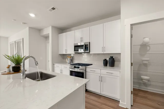 a open kitchen with stainless steel appliances a refrigerator and a stove top oven