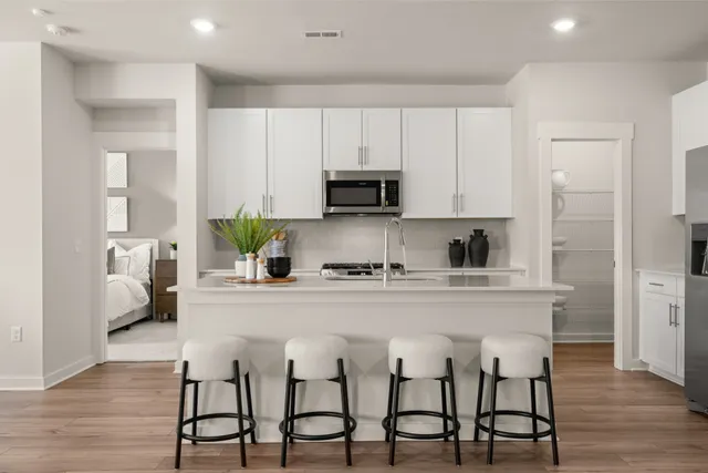 a large kitchen with kitchen island granite countertop a stove a sink a dining table and chairs with wooden floor