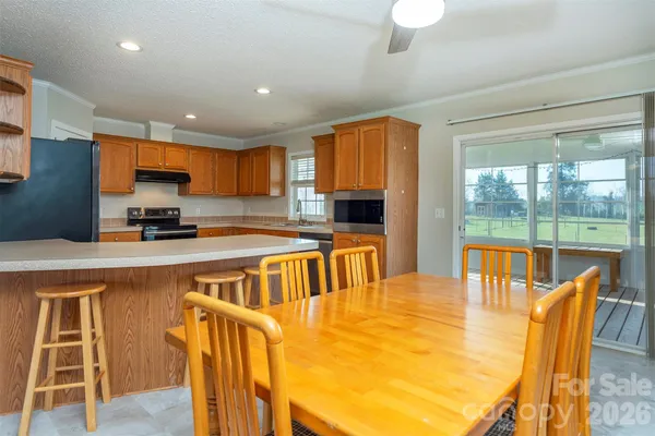 a kitchen with stainless steel appliances granite countertop a stove top oven a sink a dining table and chairs with wooden floor