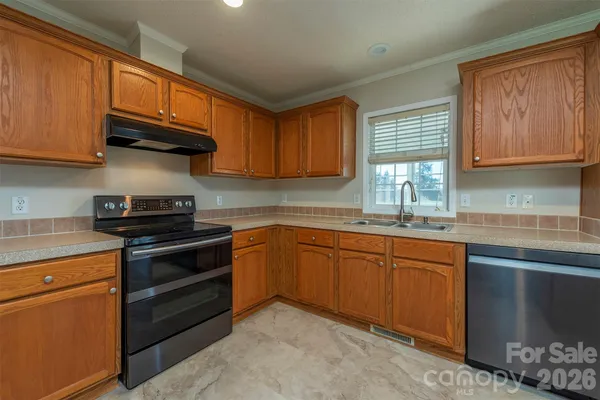 a kitchen with granite countertop wooden cabinets stainless steel appliances and a window