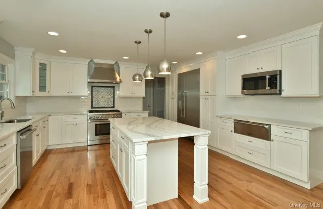 a large white kitchen with a refrigerator a sink dishwasher and a fireplace with wooden floor
