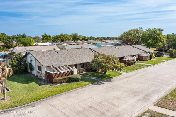 a aerial view of a house with a yard and palm trees