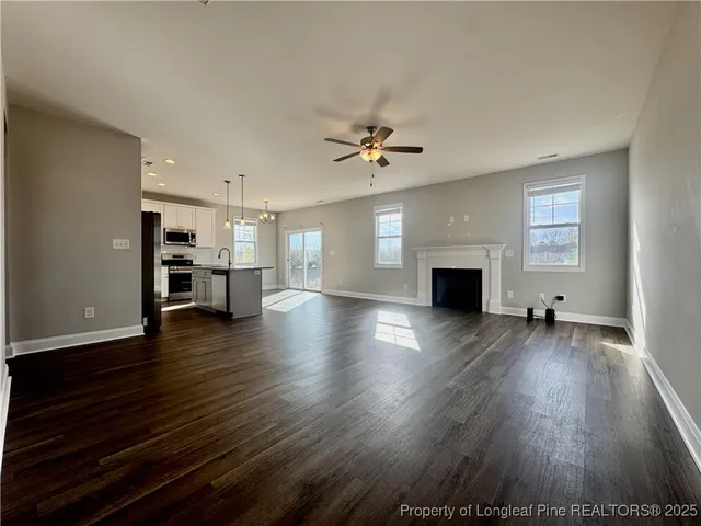 a view of a livingroom with a fireplace a ceiling fan and wooden floor