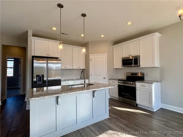 a view of a kitchen with kitchen island a sink wooden floor and a view of living room