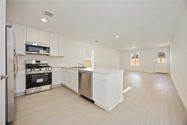 a kitchen with stainless steel appliances a stove a sink and a refrigerator