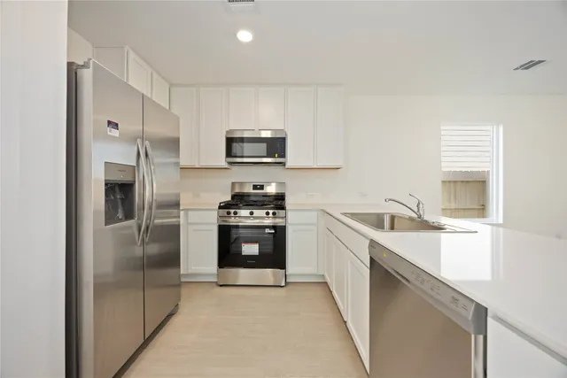 a kitchen with stainless steel appliances a refrigerator sink and stove