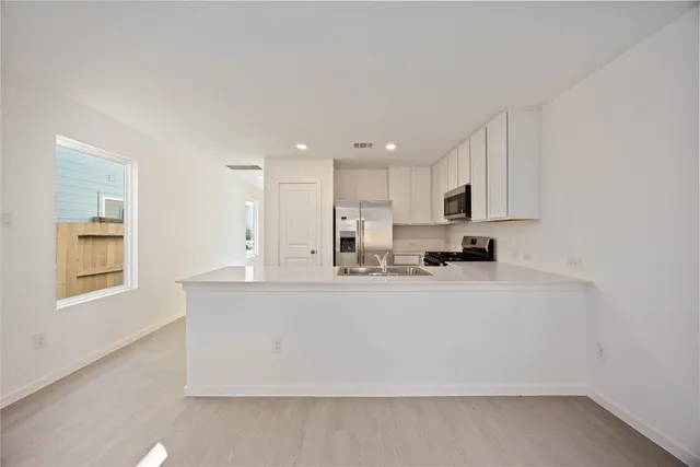 a view of kitchen with stainless steel appliances granite countertop refrigerator sink and stove
