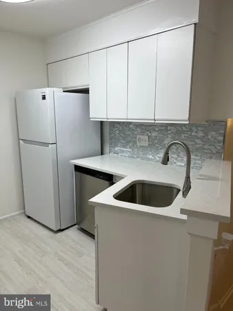 a kitchen with a sink a refrigerator and cabinets