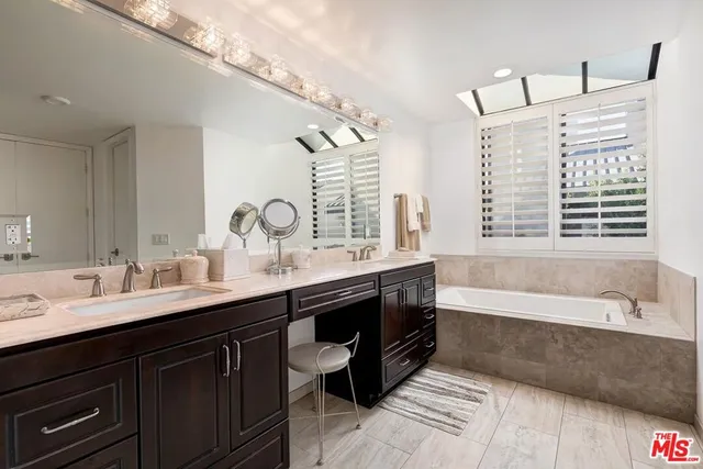 a bathroom with a double vanity sink a large mirror and bathtub