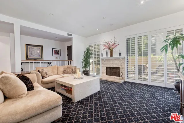 a living room with couches a fireplace and a large window