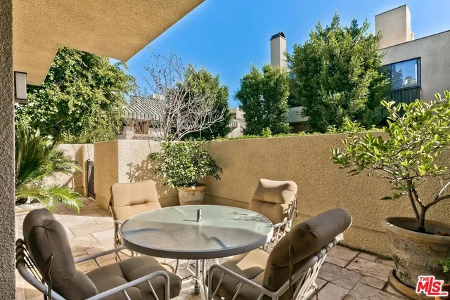 a backyard of a house with table and chairs potted plants