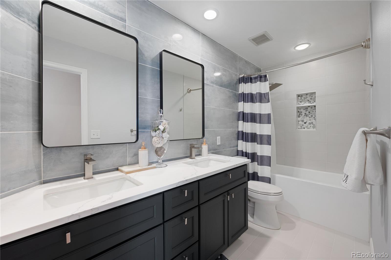 851 Hughes Lane Highlands Ranch, CO 80126 - Photo 26 of 50 a bathroom with a double vanity sink a toilet and a large mirror